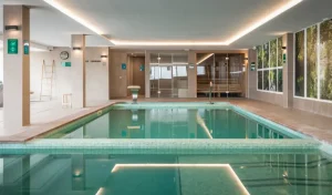 Piscina cubierta de hotel con luces LED y paredes de cristal.