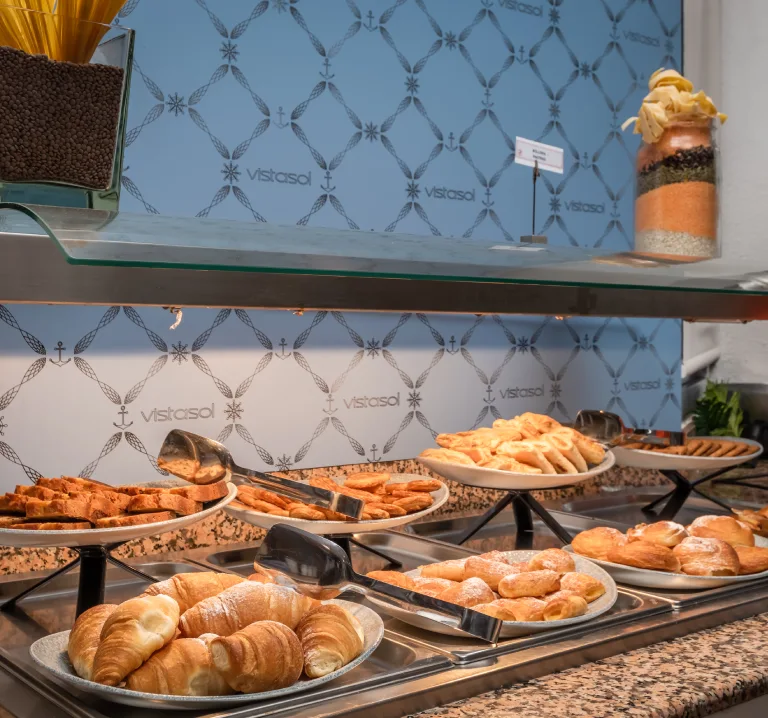 Buffet de pasteler&iacute;a con croissants y pan en vitrina para desayuno.