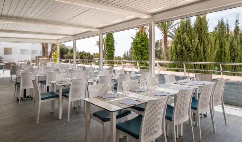 Terraza con mesas y sillas para banquete, junto a jard&iacute;n y piscina.
