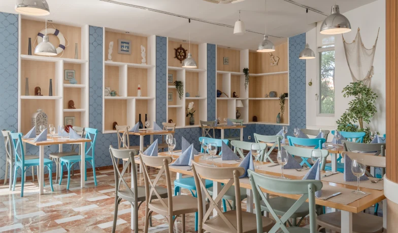 Comedor luminoso con mesas y sillas azules y blancas en un interior moderno.