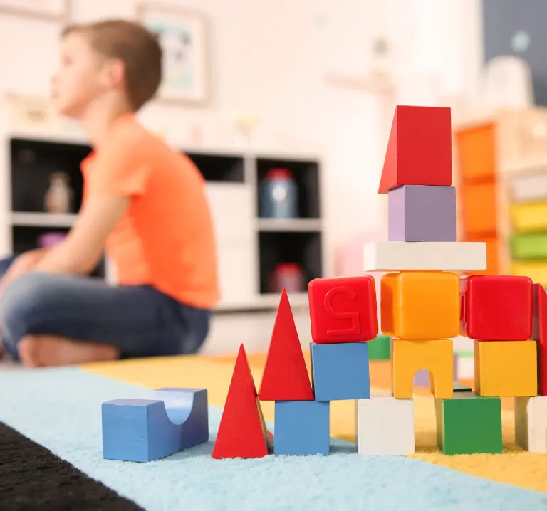 Ni&ntilde;a jugando con bloques de colores en una sala infantil