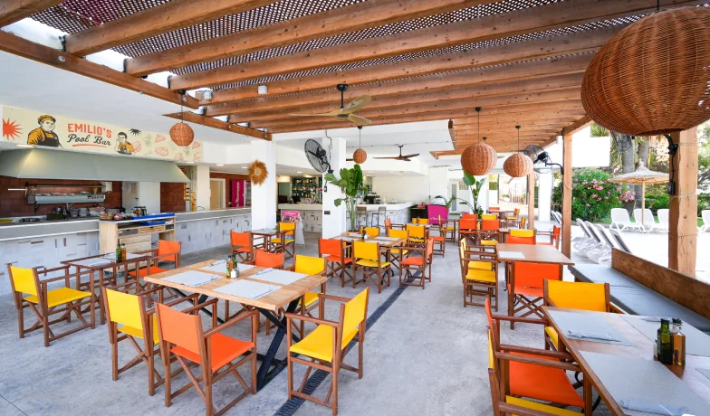 Restaurante con mesas y sillas naranjas, techo de madera y c&uacute;pula de mimbre.