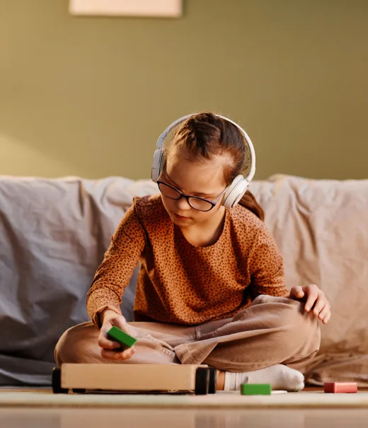 Ni&ntilde;a con auriculares usa tablet y estudio en la mesa con libros