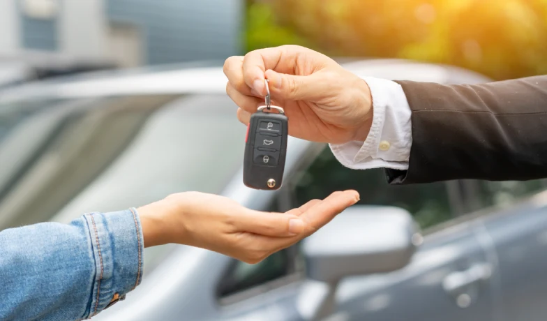 Persona entrega un control remoto de coche con mano extendida.