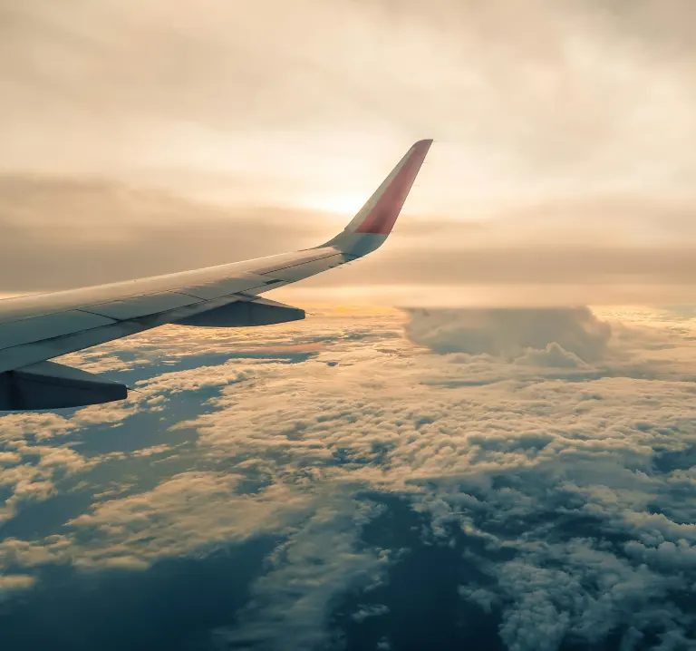 Vista desde el avi&oacute;n: ala sobre nubes al atardecer