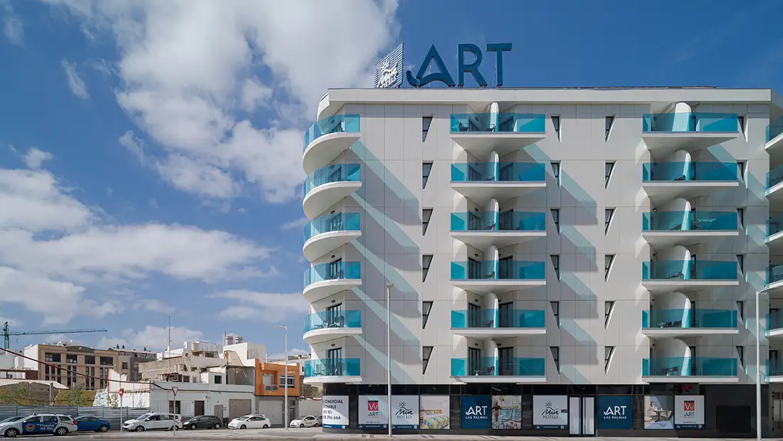 Fachada de hotel moderno con balcones y letrero &ldquo;ART&rdquo; en cielo azul