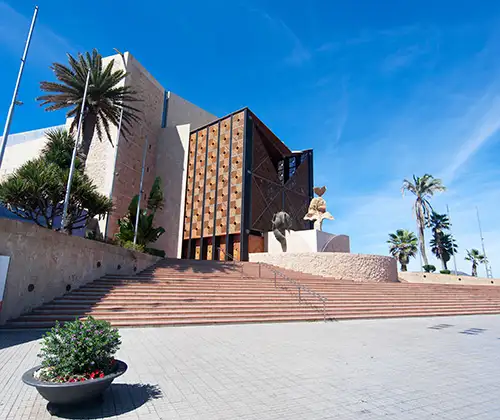 Escalinata y edificios modernos con palmeras bajo cielo azul despejado.