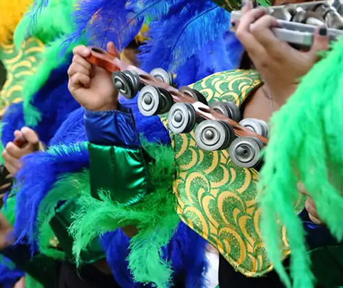 Personas pintando un traje azul y verde con adornos y rodillos met&aacute;licos.