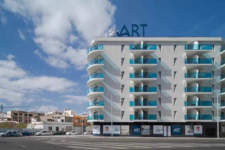 Edificio ART con balcones y letrero, cielo azul y nubes en la ciudad