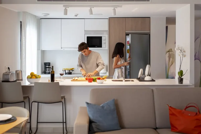 Cocina moderna: pareja prepara comida sobre la encimera blanca.