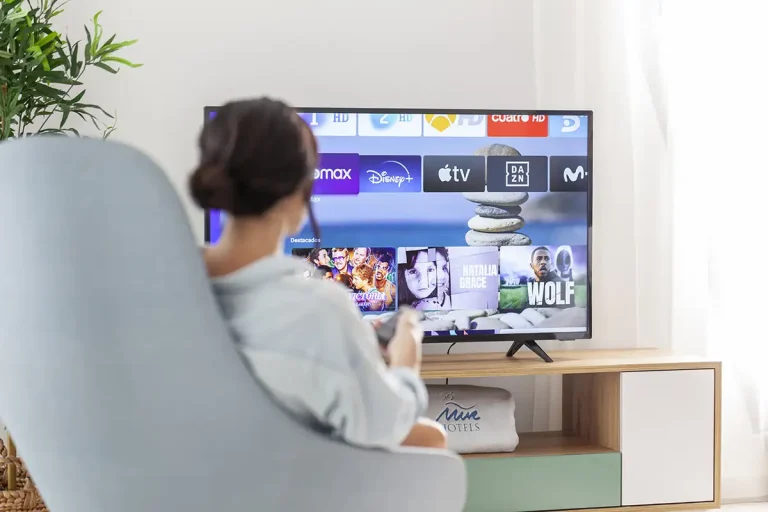 Persona viendo televisi&oacute;n en pantalla con apps de streaming y canales