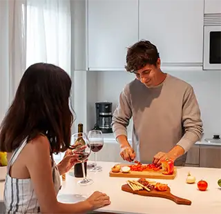 Hombre sirve vino y prepara una cena con comida en la mesa
