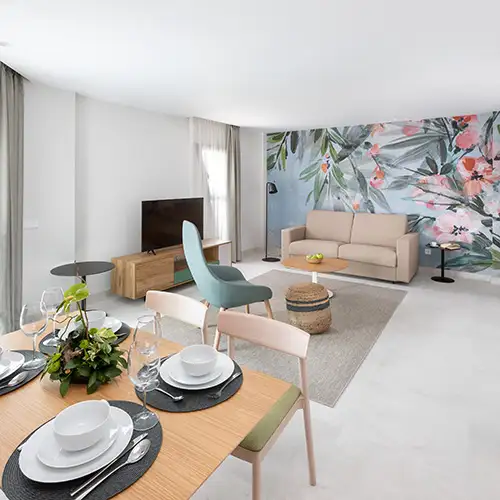 Sala de estar moderna con sof&aacute; beige y mesa con vajilla decorativa.