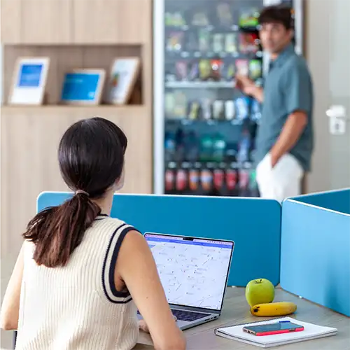 Persona con laptop en mostrador, gerente atendiendo en tienda de bebidas