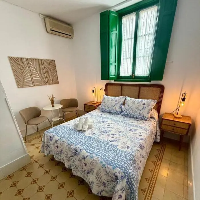 Dormitorio con cama doble, cabecero de madera y ventana verde con cortinas