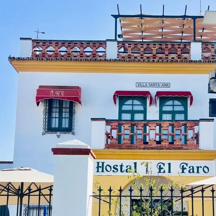 Fachada de &ldquo;Hostal El Faro&rdquo; con letrero y ventanas, cielo azul