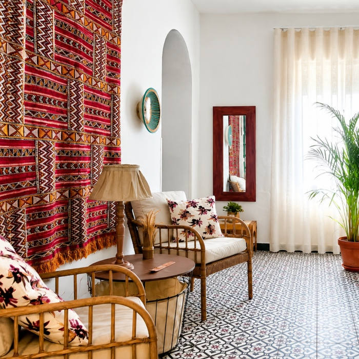 Sala de estar con tapiz colorido, cojines florales, mesa de madera y plantas.