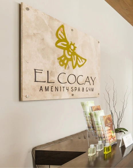 Cartel de El Cocay Amenity Spa & Gym con icono y decoraci&oacute;n en recepci&oacute;n.