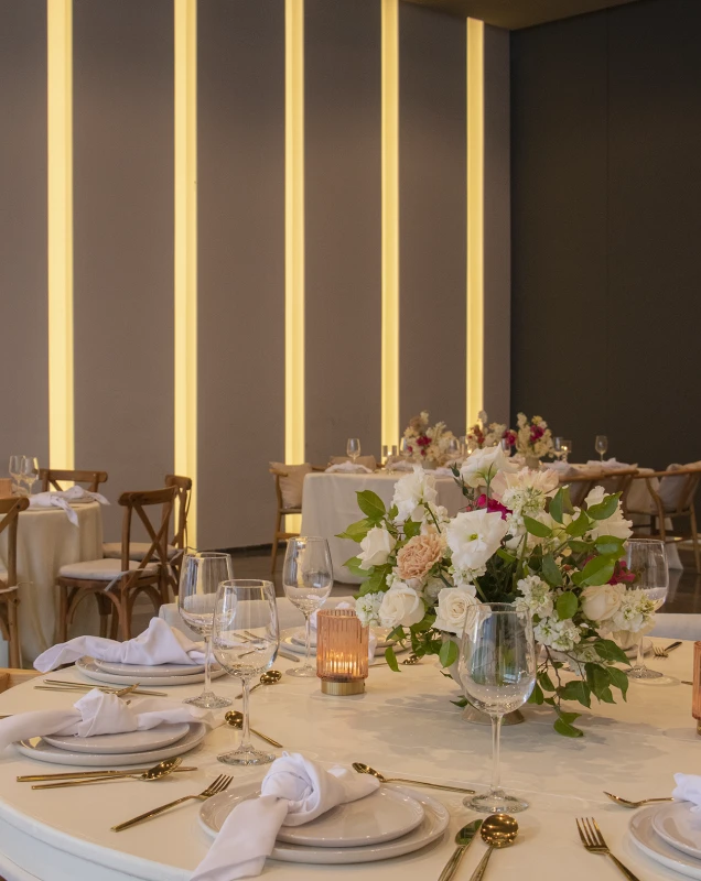 Mesa decorada con flores y copas bajo luces c&aacute;lidas en un banquete.