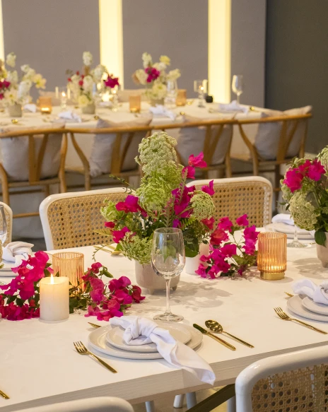 Mesa decorada con flores fucsias y velas en un evento.