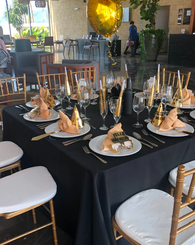 Mesa de celebraci&oacute;n de A&ntilde;o Nuevo con copas y decoraci&oacute;n dorada y servilletas.