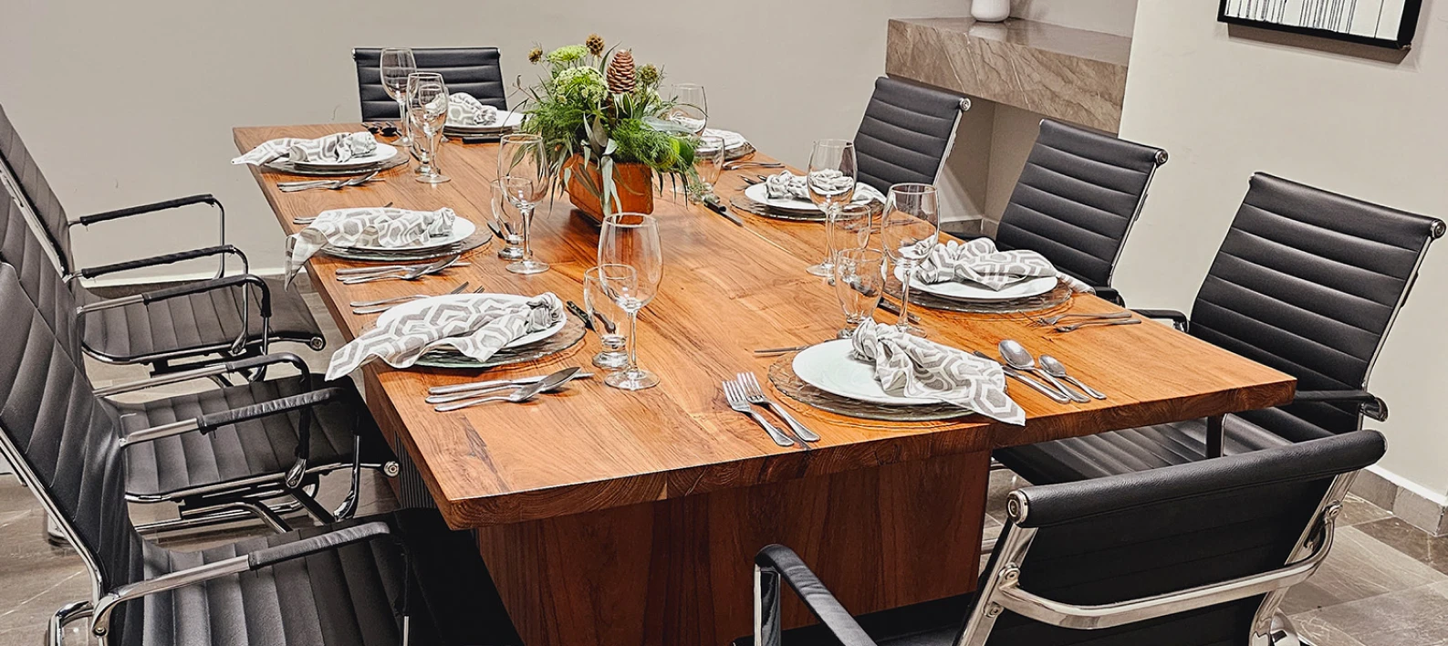 Mesa de comedor con mantel y vajilla, rodeada de sillas tapizadas negras