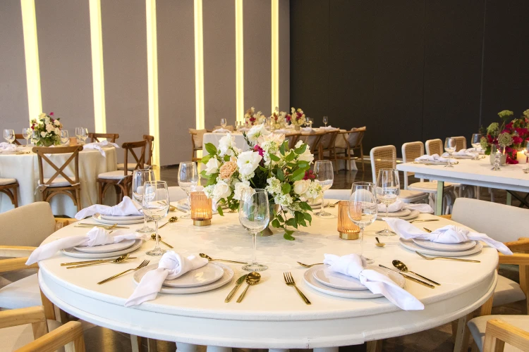 Mesa de banquete con vajilla y centros florales en evento formal.