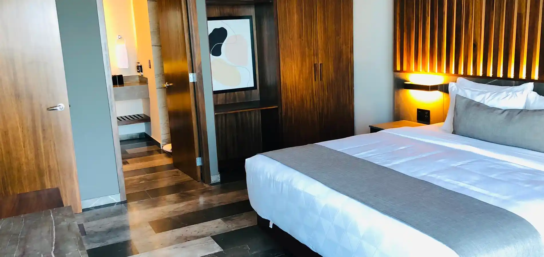 Habitaci&oacute;n de hotel con cama, luces c&aacute;lidas y puertas de madera