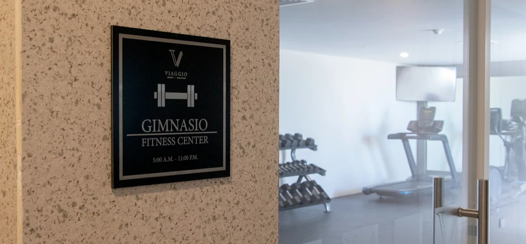 Cartel &ldquo;GIMNASIO FITNESS CENTER&rdquo; y sala con pesas y m&aacute;quinas de ejercicio.