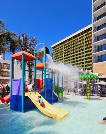 Tobog&aacute;n infantil en piscina de hotel con edificios y cielo azul