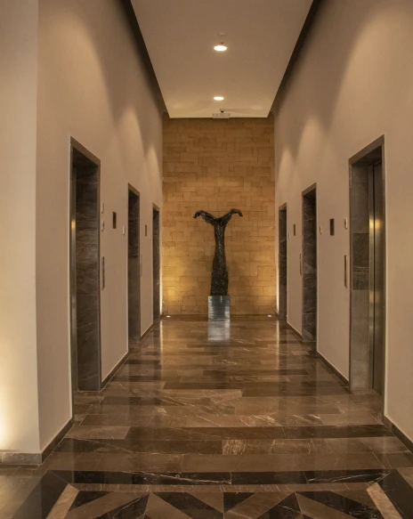 Pasillo interior con columnas, l&aacute;mparas empotradas y estatua central.
