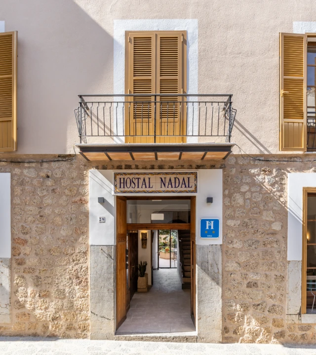 Entrada del hostal Nadal con letrero y puerta abierta en edificio de piedra.