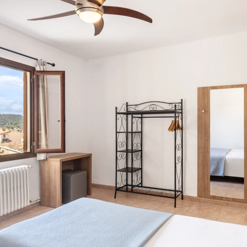 Dormitorio moderno con cama, ventilador de techo y ventana panor&aacute;mica