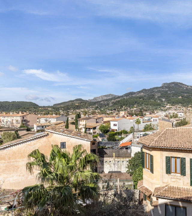 Vistas de tejados y casas en un pueblo junto a monta&ntilde;as y cielo azul