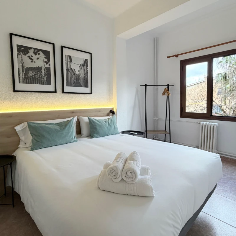 Dormitorio moderno con cama blanca, almohadas azules y dos cuadros en la pared