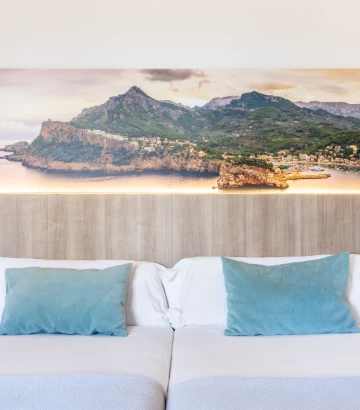 Sala con sofá blanco y cojines azules, con mural de paisaje y mar