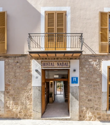 Entrada del hostal &ldquo;Nadal&rdquo; con pasillo y fachada de piedra y madera