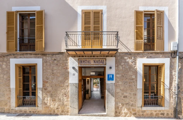 Fachada de un hostal con ventanas y puertas de persianas, &ldquo;Hostal Nadal&rdquo;.
