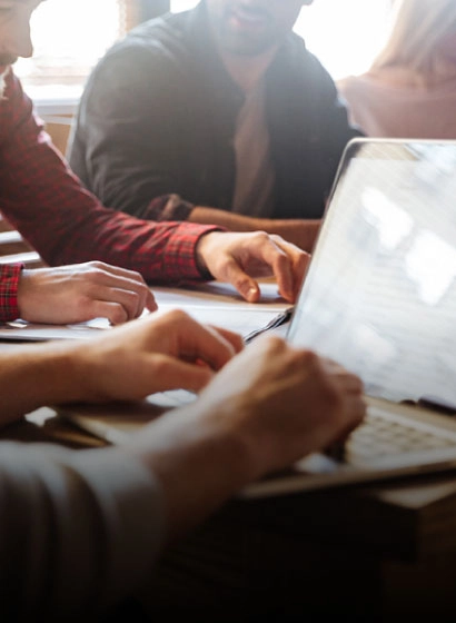 Personas trabajando en una mesa con port&aacute;tiles y documentos