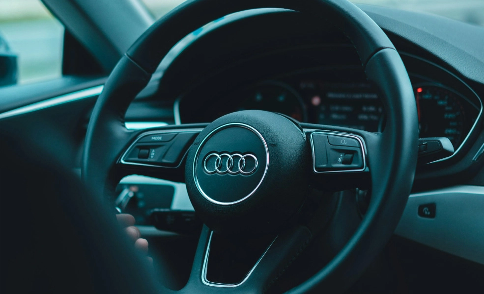 Volante de Audi con emblema y panel de instrumentos en el interior del coche.