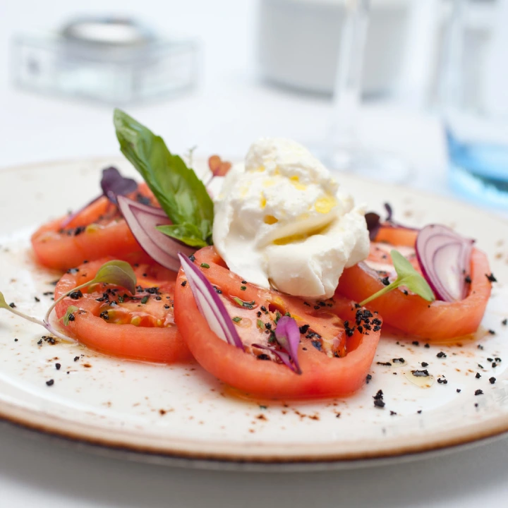 Tomates con cebolla morada y queso crema, con hierbas y pimienta negra.