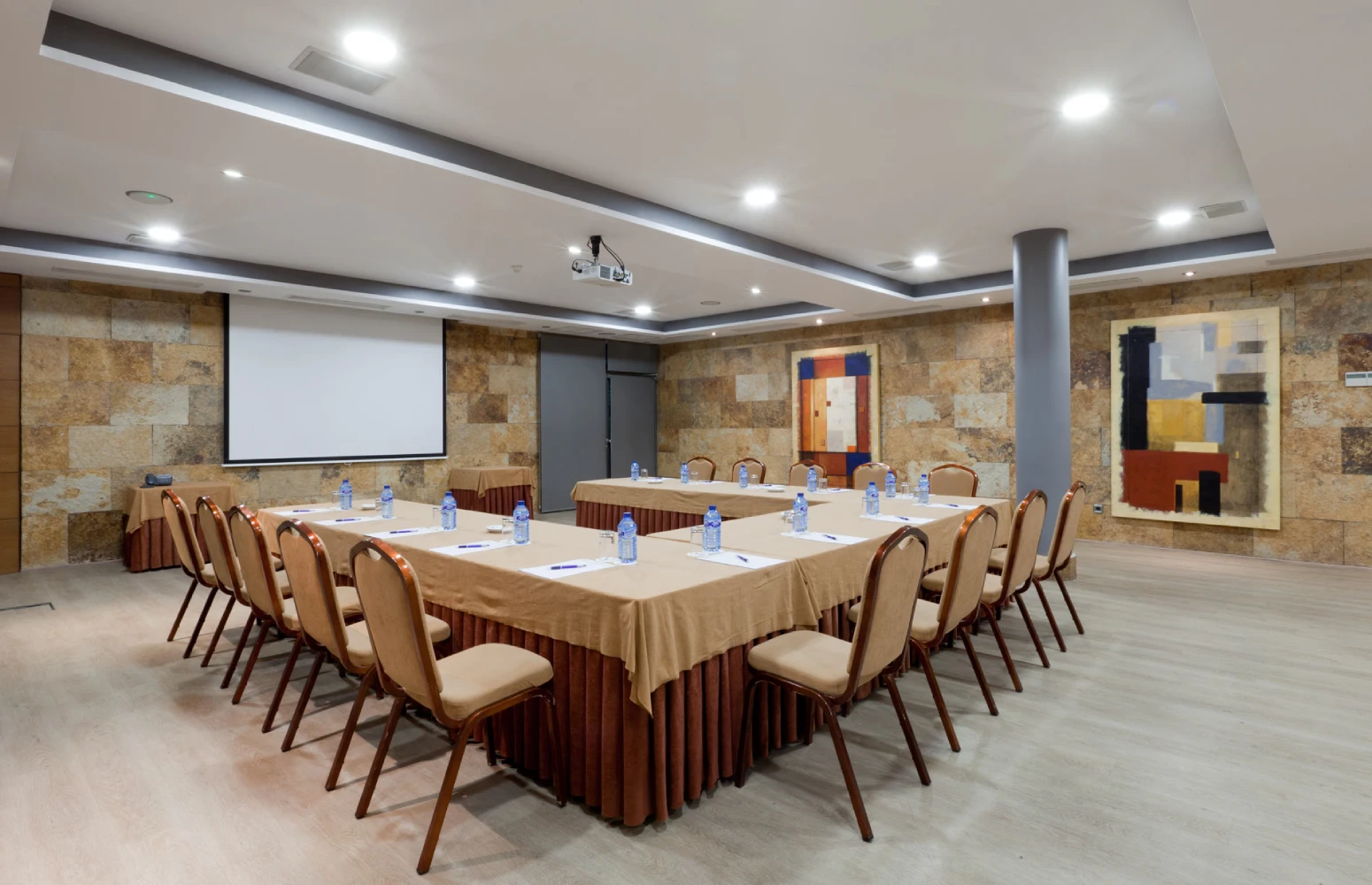 Sala de reuniones con mesas rectangulares, sillas y proyector en techo