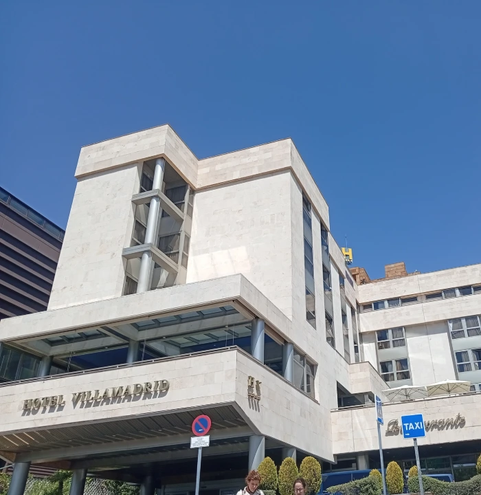Hotel Villa Madrid, fachada de edificio blanco con cielo azul al fondo.