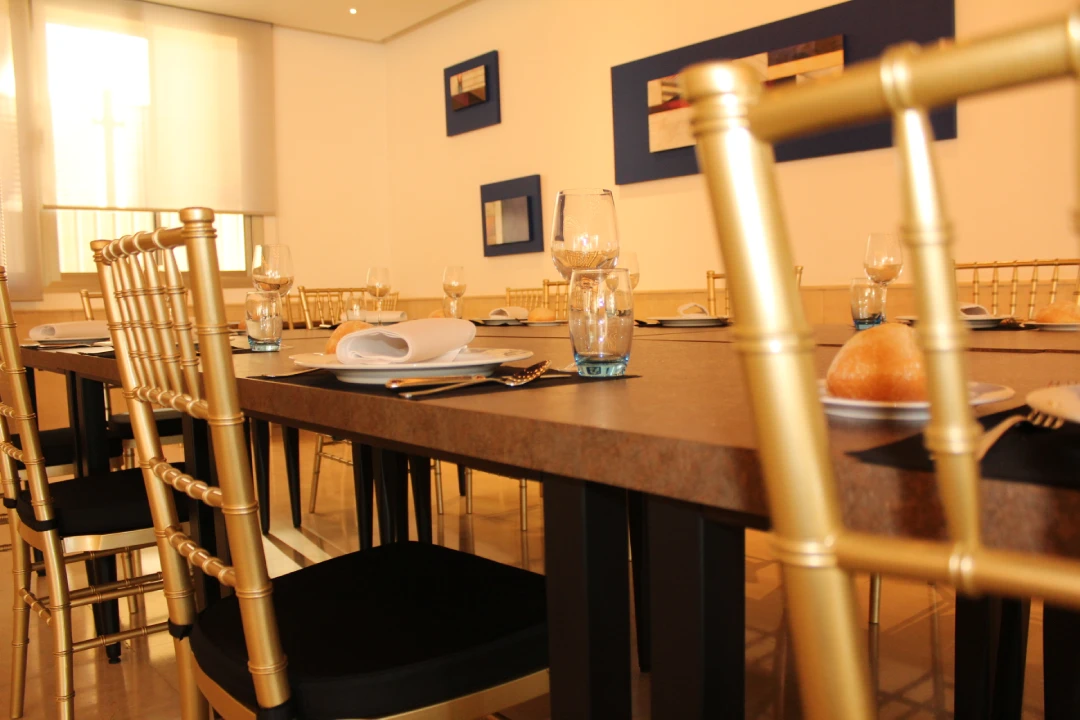 Comedor con mesa servida, sillas doradas y copas en una sala elegante