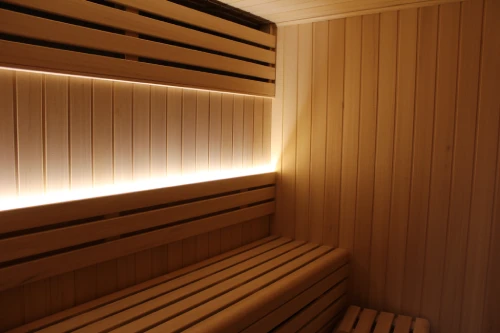 Interior de una sauna con bancos y luz c&aacute;lida en madera.