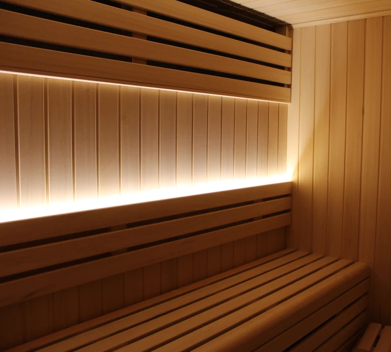 Interior de sauna de madera con bancos y luz c&aacute;lida.