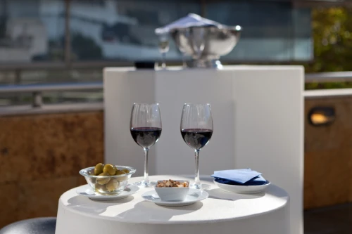 Mesa con dos copas de vino y aperitivos en terraza al aire libre.