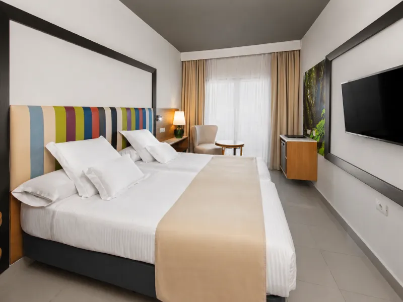 Habitaci&oacute;n de hotel moderna con cama doble y televisor de pared