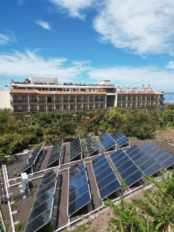 Hotel costero con paneles solares y cielo nublado azul.