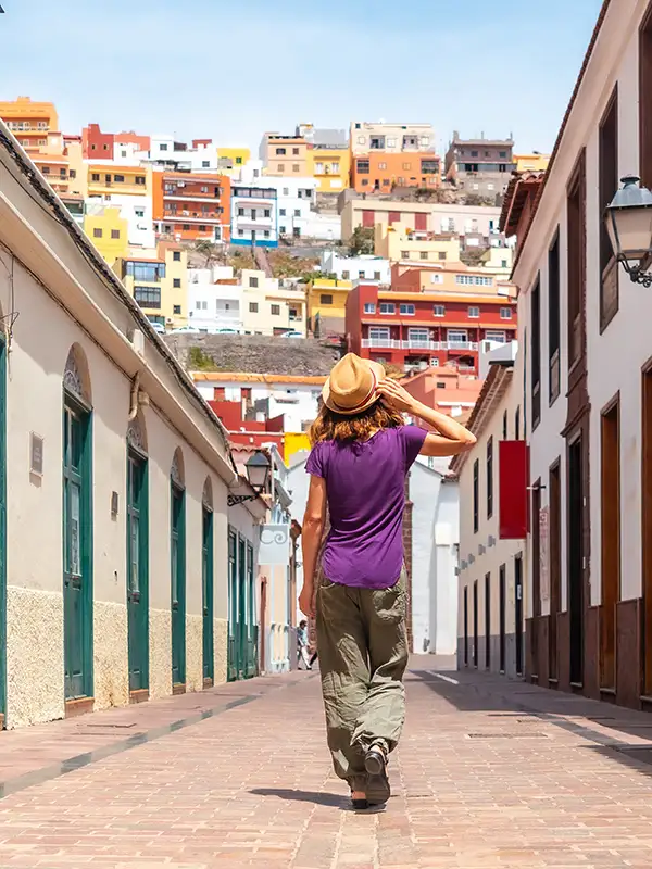 Persona caminando por un callej&oacute;n con casas de colores al fondo